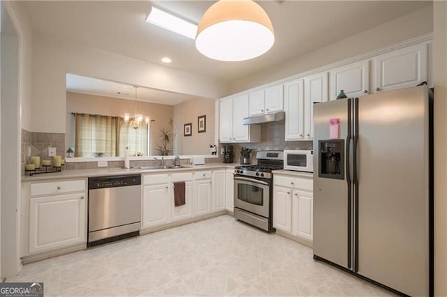 kitchen with tasteful backsplash, decorative light fixtures, appliances with stainless steel finishes, a notable chandelier, and white cabinets