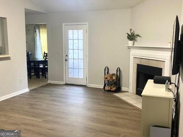 living area with a fireplace, wood finished floors, and baseboards