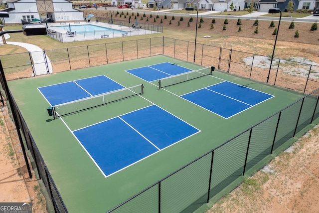 view of tennis court with a community pool