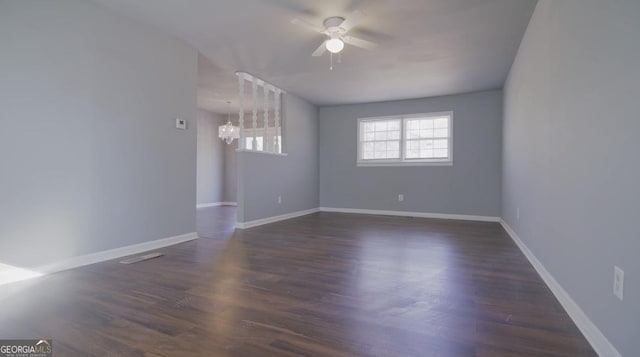 spare room featuring dark wood-type flooring and ceiling fan with notable chandelier