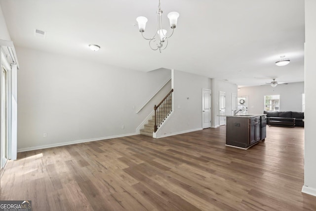 unfurnished living room featuring sink, ceiling fan with notable chandelier, and dark wood-type flooring