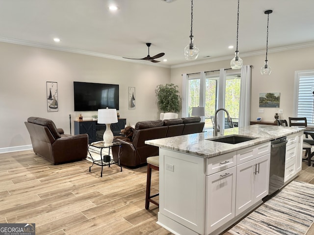 kitchen with sink, white cabinetry, light stone counters, dishwashing machine, and an island with sink