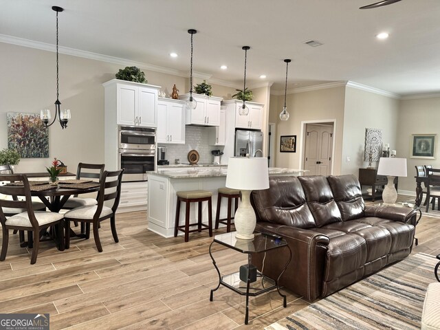 kitchen featuring pendant lighting, sink, white cabinetry, stainless steel refrigerator with ice dispenser, and a center island with sink