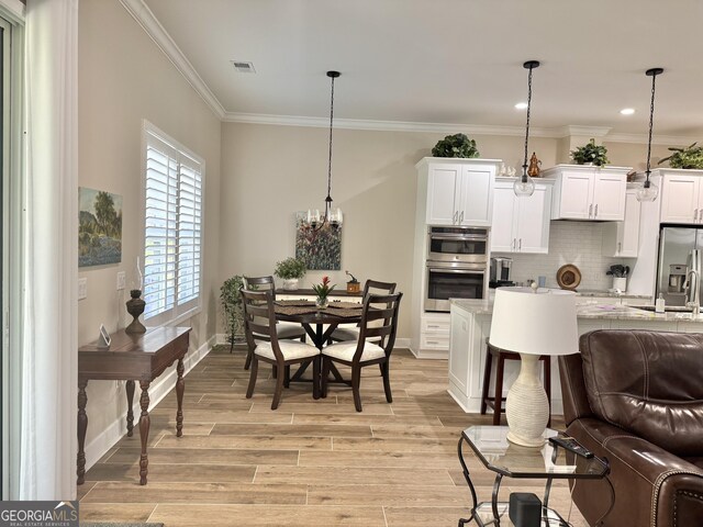 living room featuring crown molding, an inviting chandelier, and light hardwood / wood-style floors