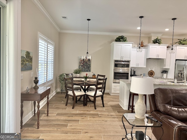 kitchen featuring white cabinetry, light stone counters, hanging light fixtures, light wood-type flooring, and appliances with stainless steel finishes