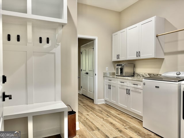 clothes washing area with cabinets, light hardwood / wood-style floors, and washing machine and dryer