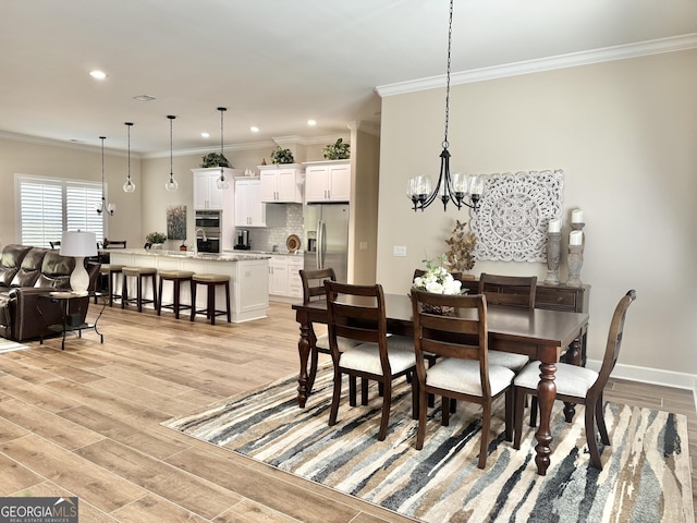 dining space with crown molding, a chandelier, and light hardwood / wood-style floors