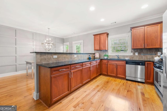 kitchen with sink, appliances with stainless steel finishes, dark stone countertops, decorative light fixtures, and kitchen peninsula