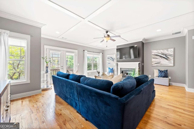 living room with light hardwood / wood-style flooring, ceiling fan, coffered ceiling, ornamental molding, and french doors