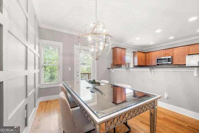 dining space with ornamental molding, a chandelier, and light wood-type flooring