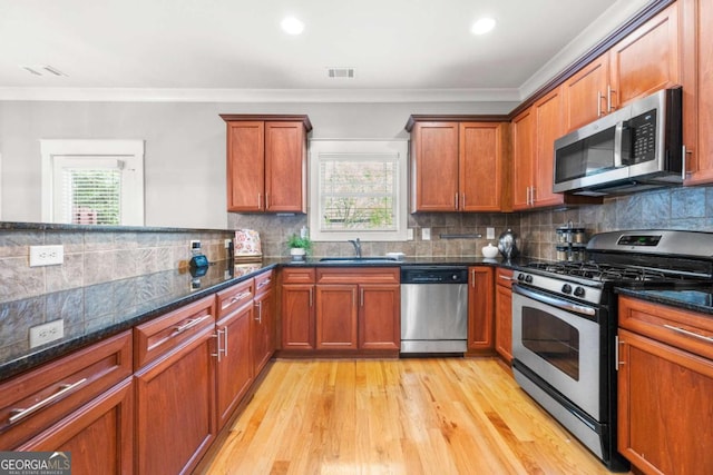 kitchen featuring crown molding, dark stone counters, and appliances with stainless steel finishes