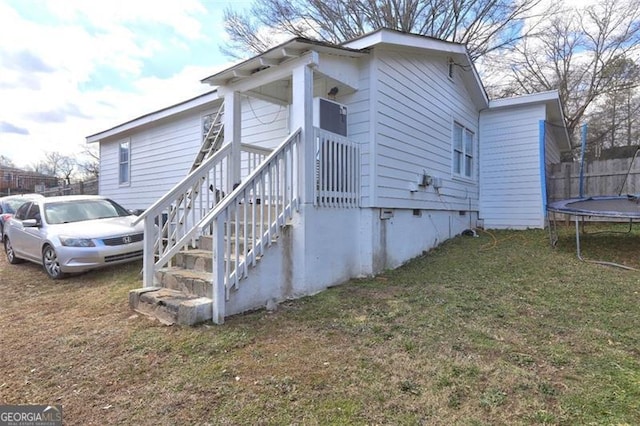 view of side of home with a yard and a trampoline