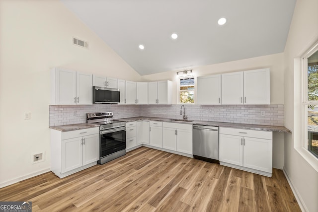 kitchen with sink, tasteful backsplash, high vaulted ceiling, stainless steel appliances, and white cabinets