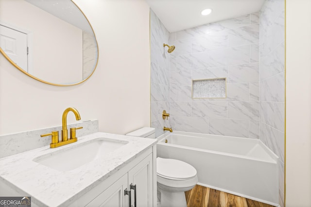 full bathroom featuring hardwood / wood-style flooring, tiled shower / bath, vanity, and toilet