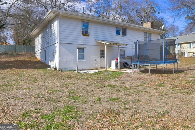 back of property featuring a trampoline and a yard