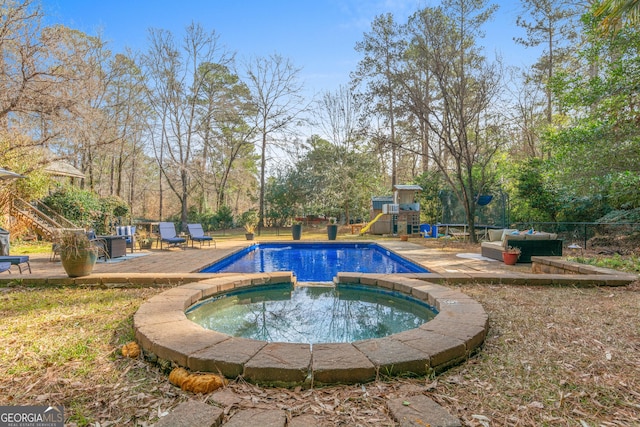 view of pool with a pool with connected hot tub, a playground, and fence