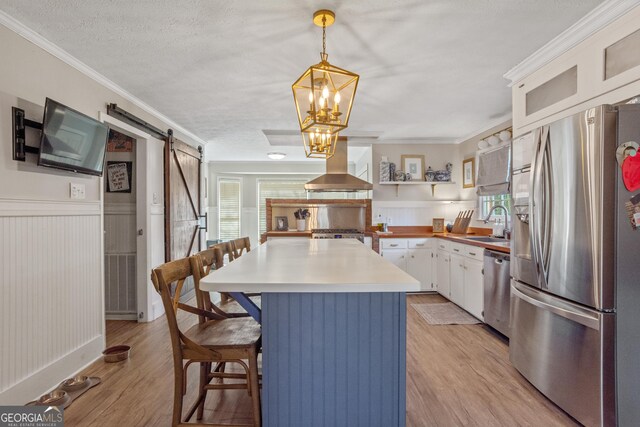 kitchen featuring pendant lighting, white cabinetry, sink, exhaust hood, and stainless steel appliances