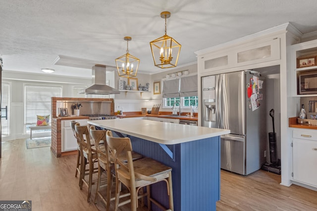 kitchen with hanging light fixtures, glass insert cabinets, white cabinets, island range hood, and stainless steel fridge with ice dispenser