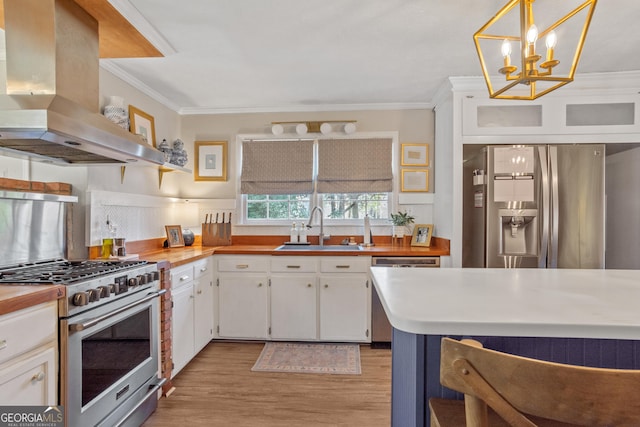 kitchen with white cabinets, island range hood, stainless steel appliances, and decorative light fixtures