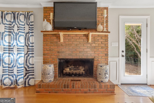 living area with ornamental molding, a fireplace, and wood finished floors