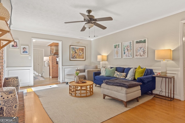 living room with wainscoting, wood finished floors, and crown molding