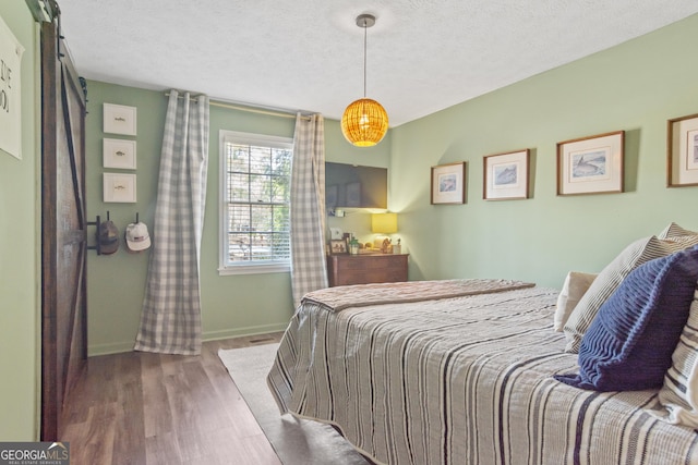 bedroom featuring a textured ceiling, baseboards, and wood finished floors