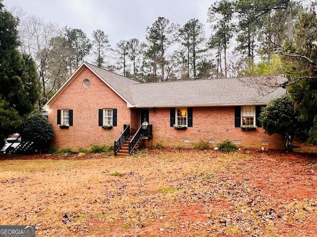 ranch-style house featuring crawl space, brick siding, and roof with shingles