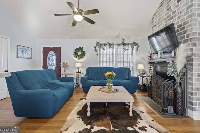 living room with lofted ceiling, a brick fireplace, and wood-type flooring