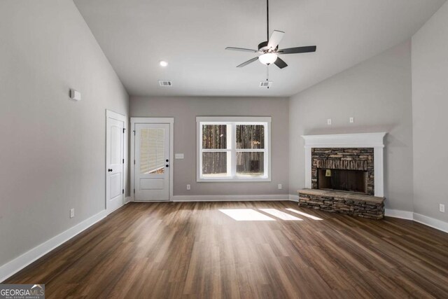 unfurnished living room featuring dark hardwood / wood-style flooring, a stone fireplace, and ceiling fan