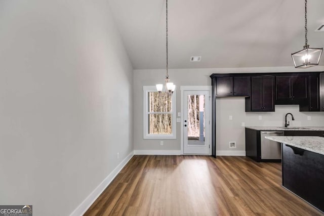 kitchen with pendant lighting, stainless steel dishwasher, light stone countertops, and an inviting chandelier