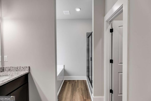 bathroom featuring vanity, hardwood / wood-style flooring, and plus walk in shower