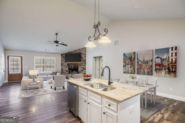 kitchen with sink, stainless steel dishwasher, an island with sink, pendant lighting, and light stone countertops