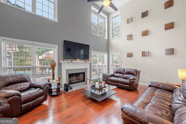 living room featuring hardwood / wood-style floors, a wealth of natural light, ceiling fan, and a high ceiling