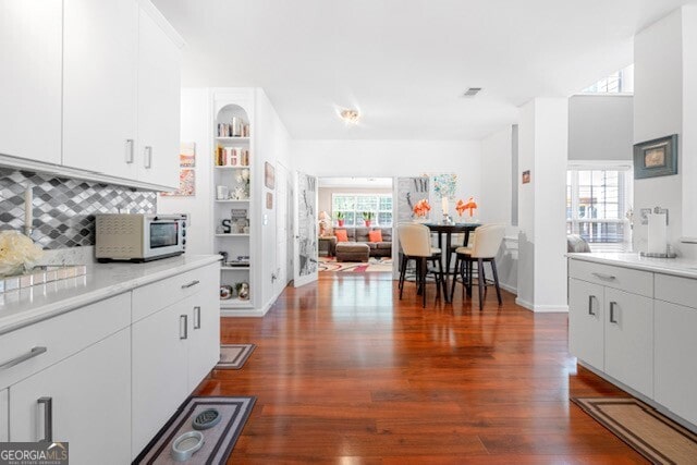 kitchen with a healthy amount of sunlight, dark wood-type flooring, and white cabinets