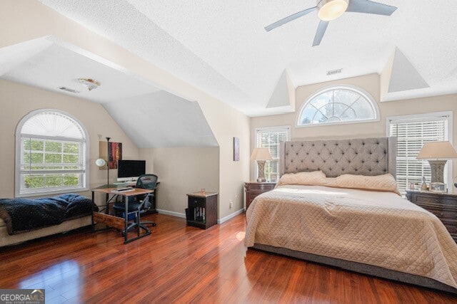 bedroom with dark hardwood / wood-style flooring, a textured ceiling, lofted ceiling, and ceiling fan