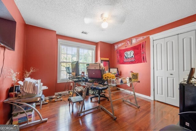 office space featuring hardwood / wood-style flooring, ceiling fan, and a textured ceiling