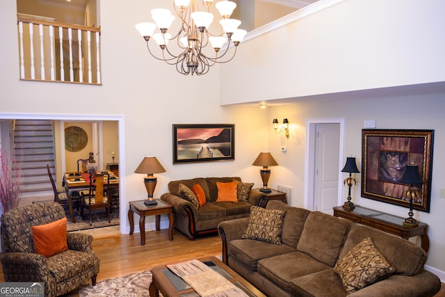 living room featuring hardwood / wood-style floors, a towering ceiling, and a notable chandelier