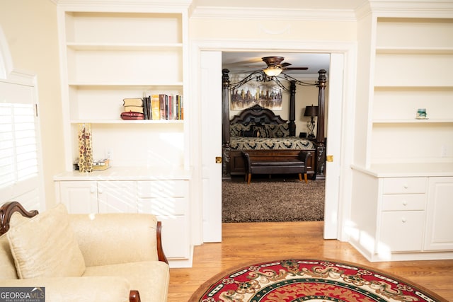 corridor featuring crown molding, built in shelves, and light hardwood / wood-style flooring