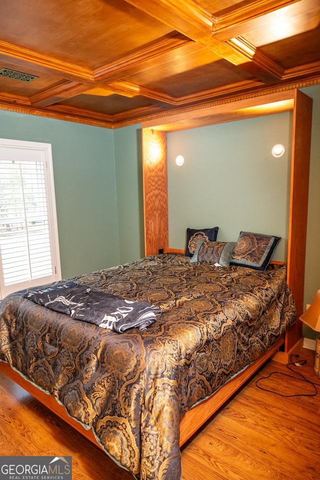bedroom featuring coffered ceiling, hardwood / wood-style flooring, ornamental molding, and beamed ceiling