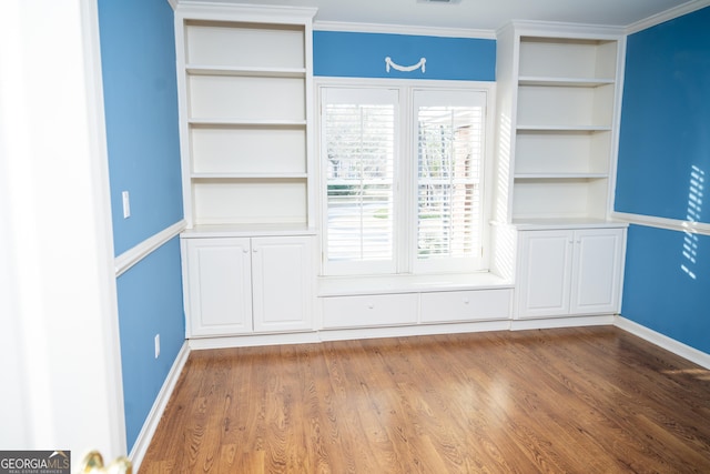 interior space with crown molding, hardwood / wood-style floors, and built in features