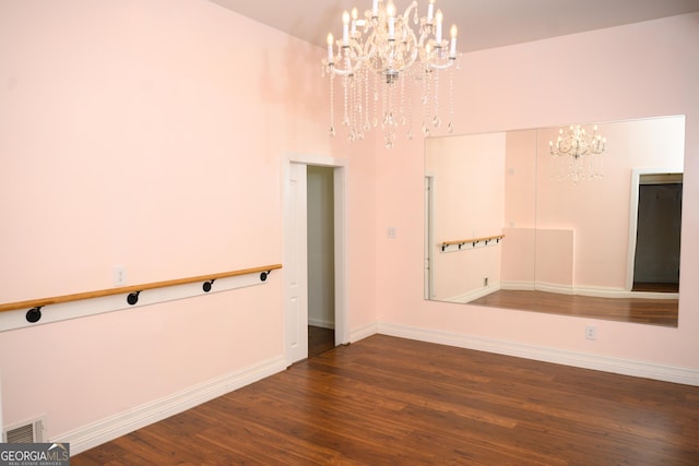 empty room with dark hardwood / wood-style floors and a notable chandelier
