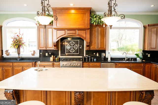 kitchen with appliances with stainless steel finishes, sink, decorative backsplash, ornamental molding, and a center island
