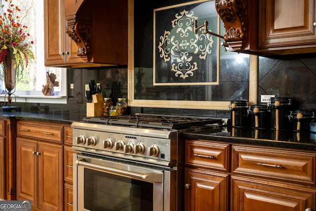 kitchen with dark stone countertops, stainless steel range with gas stovetop, and decorative backsplash