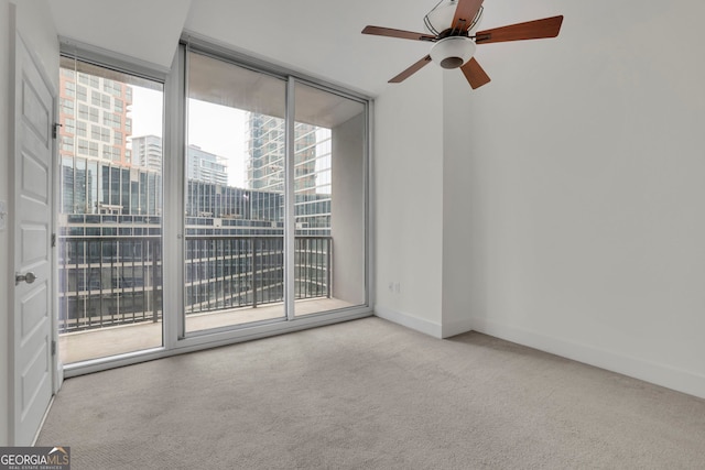 carpeted spare room featuring ceiling fan and a wall of windows