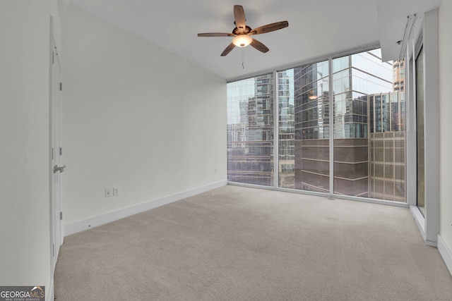 carpeted empty room with ceiling fan and expansive windows