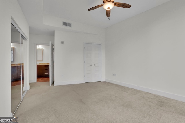 unfurnished bedroom featuring ceiling fan, light carpet, and connected bathroom