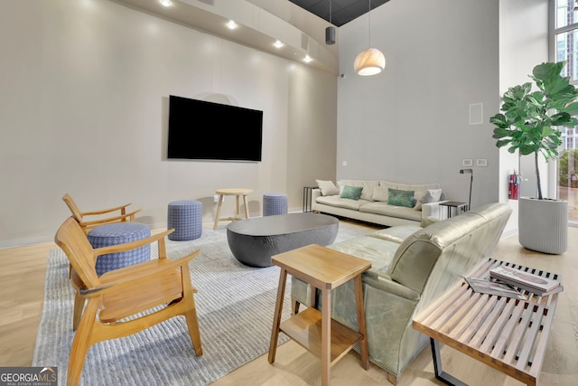 living room featuring light wood-type flooring and a towering ceiling