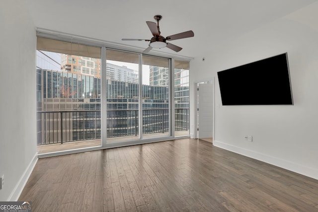 spare room featuring hardwood / wood-style flooring, a wall of windows, and ceiling fan