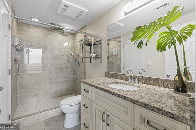 bathroom featuring a shower with door, vanity, and toilet