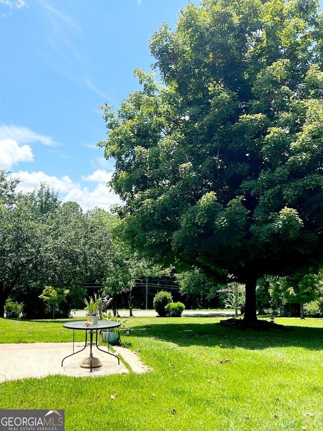 view of property's community featuring a lawn and a patio